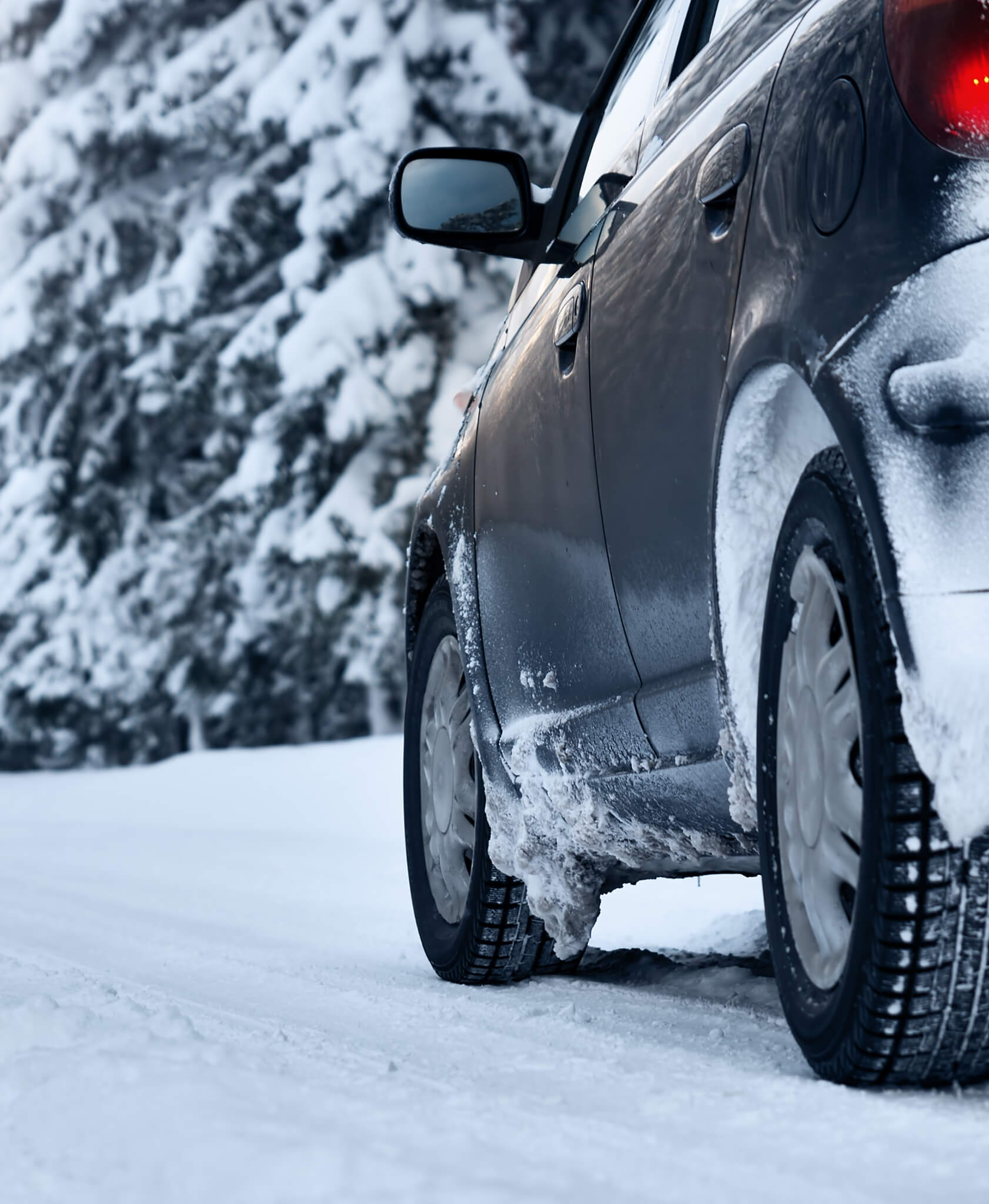 A silver car driving on a snowy road